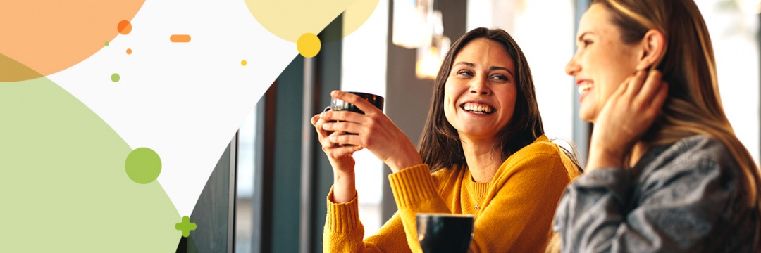Two young ladies chatting with each other while having coffee