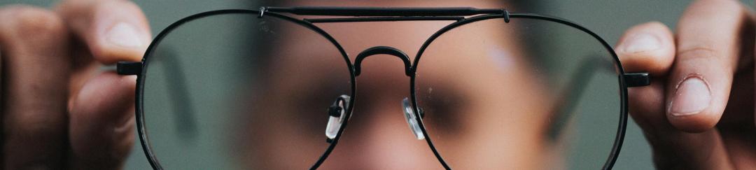 man holding glasses in front of his face