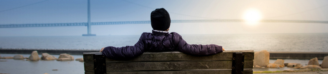 Woman sitting on a bench watching the sun set over the ocean