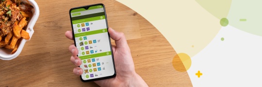 Hand holding a phone with the mySugr app log screen over a table with food