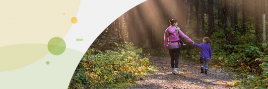 Mother and daughter holding hands while walking through a forest