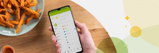 Person holding a phone with the mySugr app next to a dish of sweet potato fries