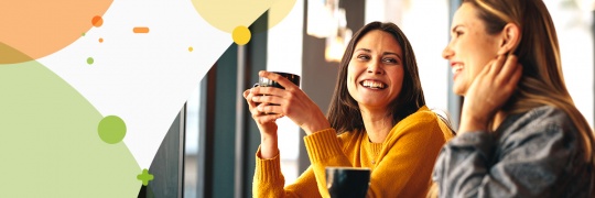 Two young ladies chatting with each other while having coffee