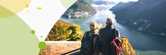 back view of couple sitting and looking down a lake