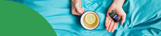 Hand mit Blutzuckermessgerät und Tee
