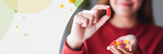 Women showing red gummy bear to the camera